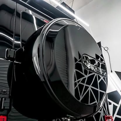 A black tire cover is attached to the back of a black car.