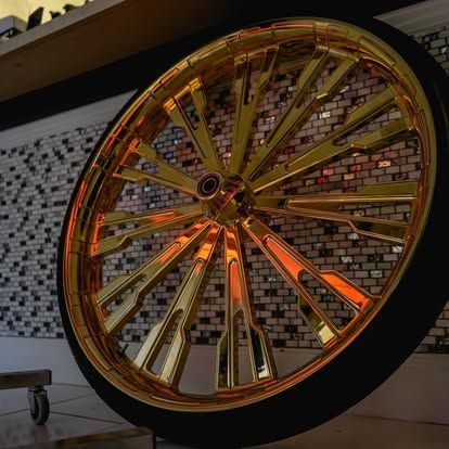 A large gold wheel is sitting in front of a brick wall
