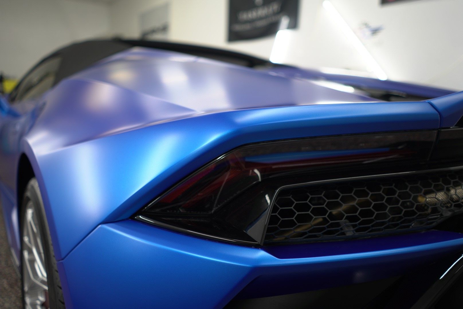 Blue sports car rear with sleek taillights in a showroom-like setting