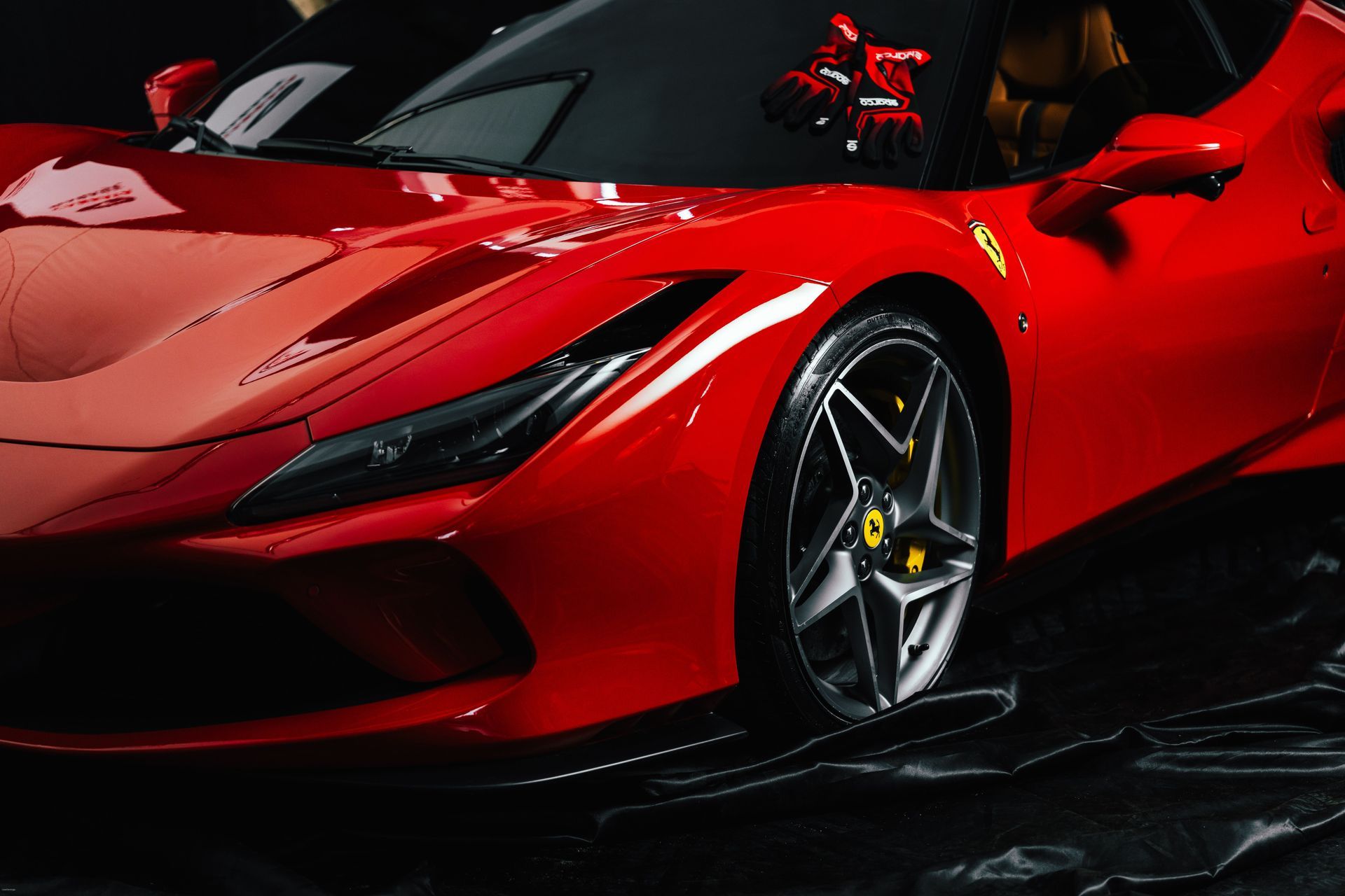 Red sports car with sleek design and black accents, shown in a dark studio setting