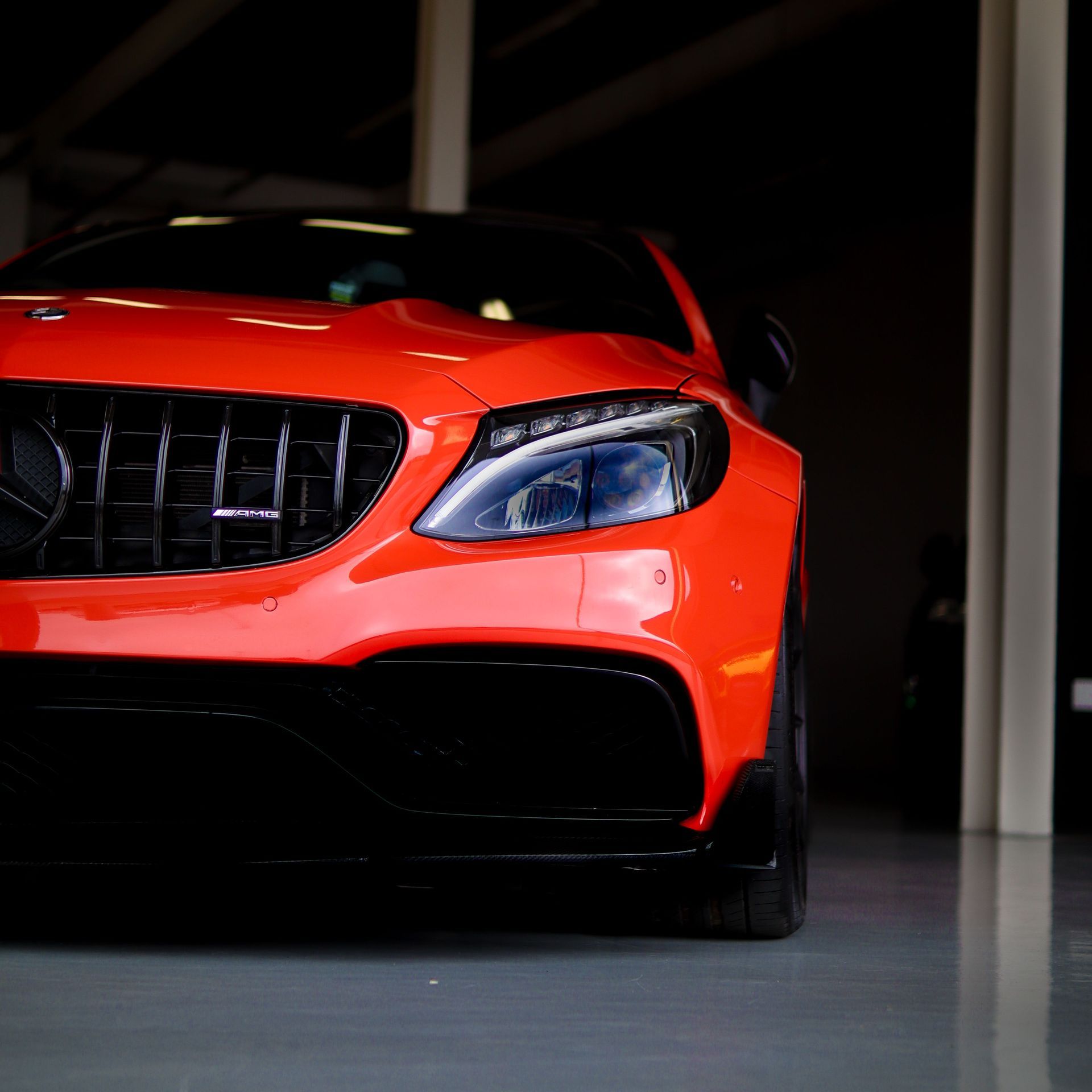 Front view of a red sports car parked indoors under dim lighting