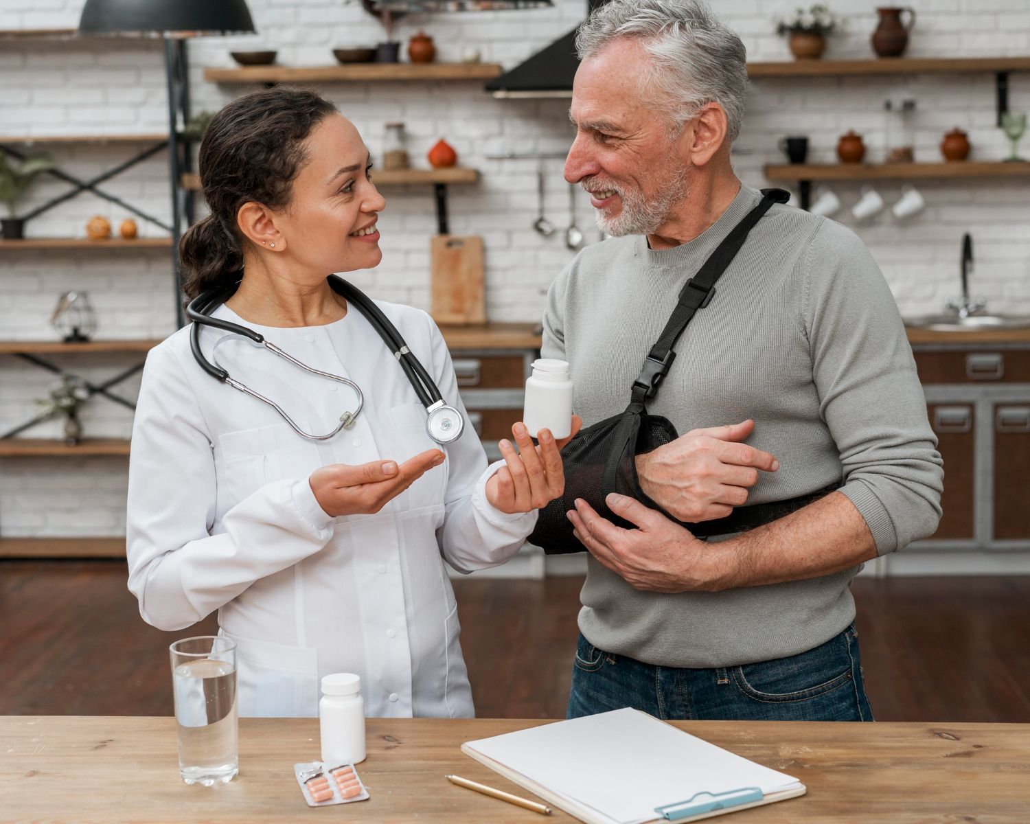 Doctor and patient talking in a clinic, smiling beside a table with medicine bottles and a notebook.