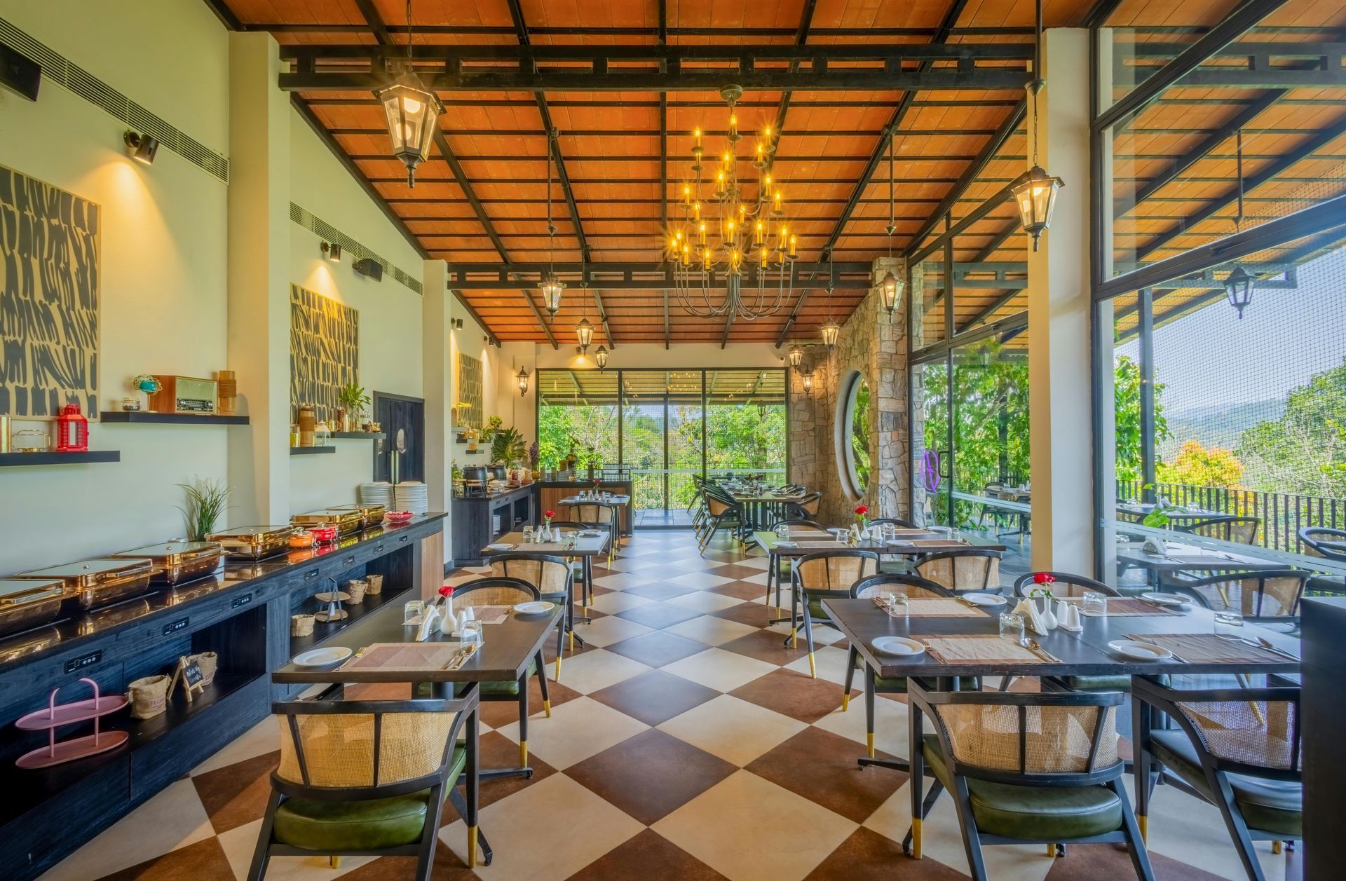 Open-air restaurant with checkered floor, wooden tables, and warm lighting overlooking greenery