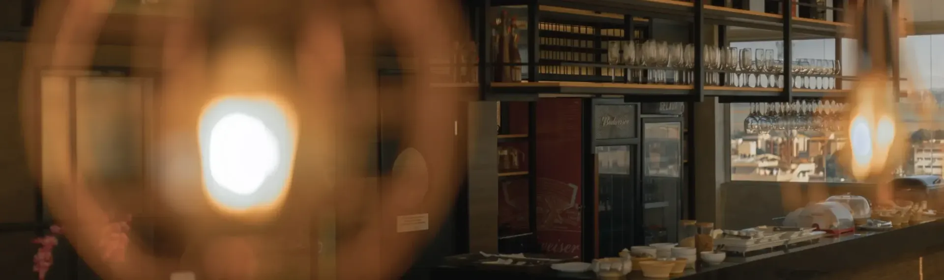Livraria aconchegante e com iluminação suave, com estantes de livros e lâmpadas brilhantes em primeiro plano.