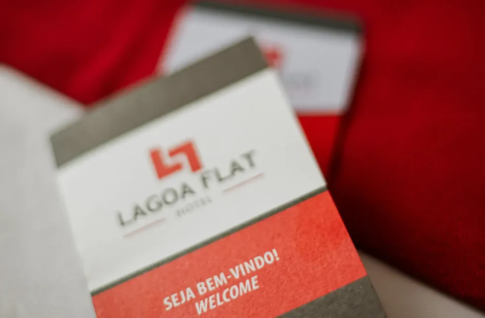 Hotel welcome card with Lagoa Flat logo on a red background, reading “Seja bem-vindo! Welcome”