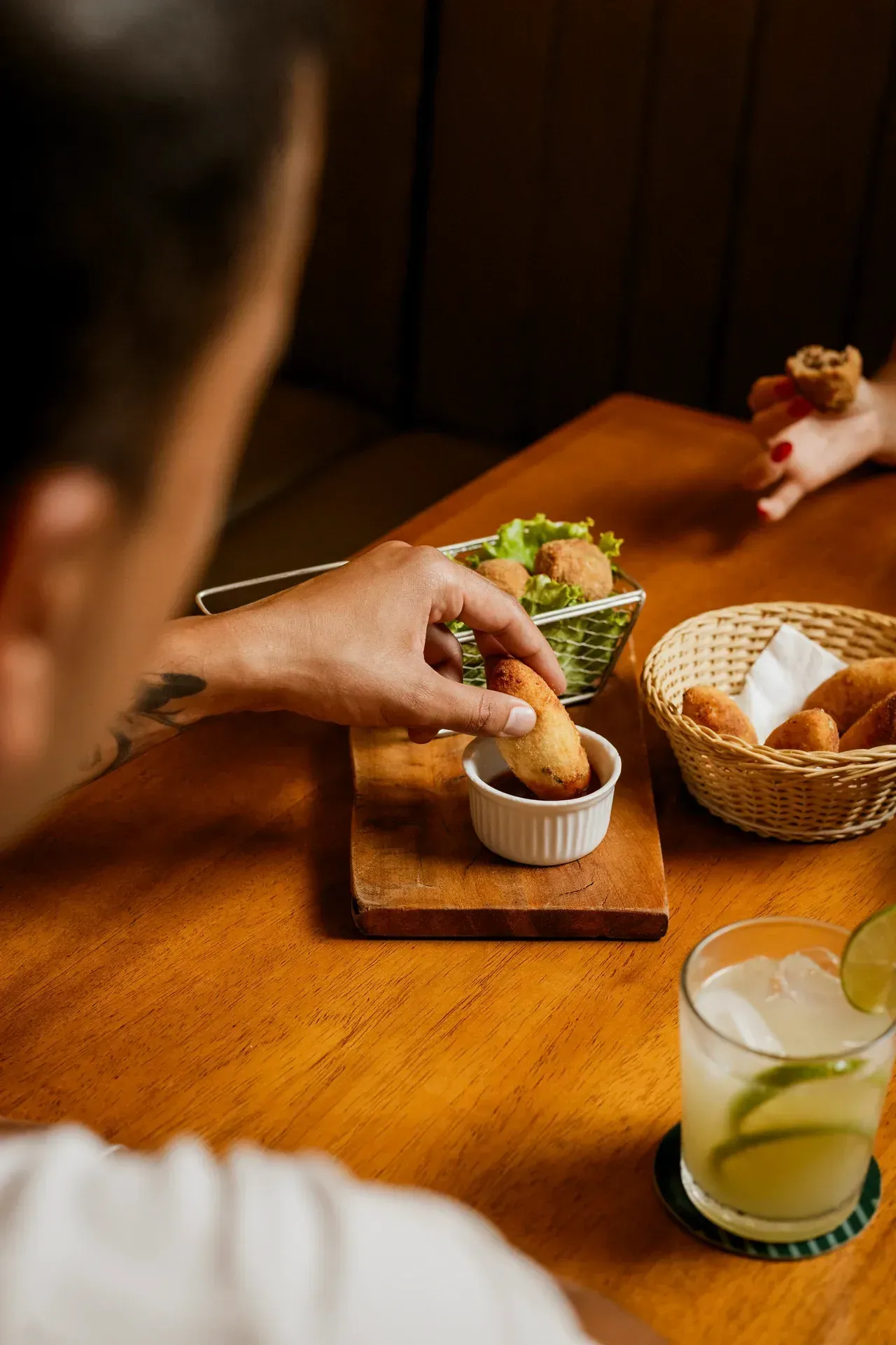 Duas pessoas jantando em um restaurante com iluminação aconchegante, uma servindo a refeição e sorrindo.