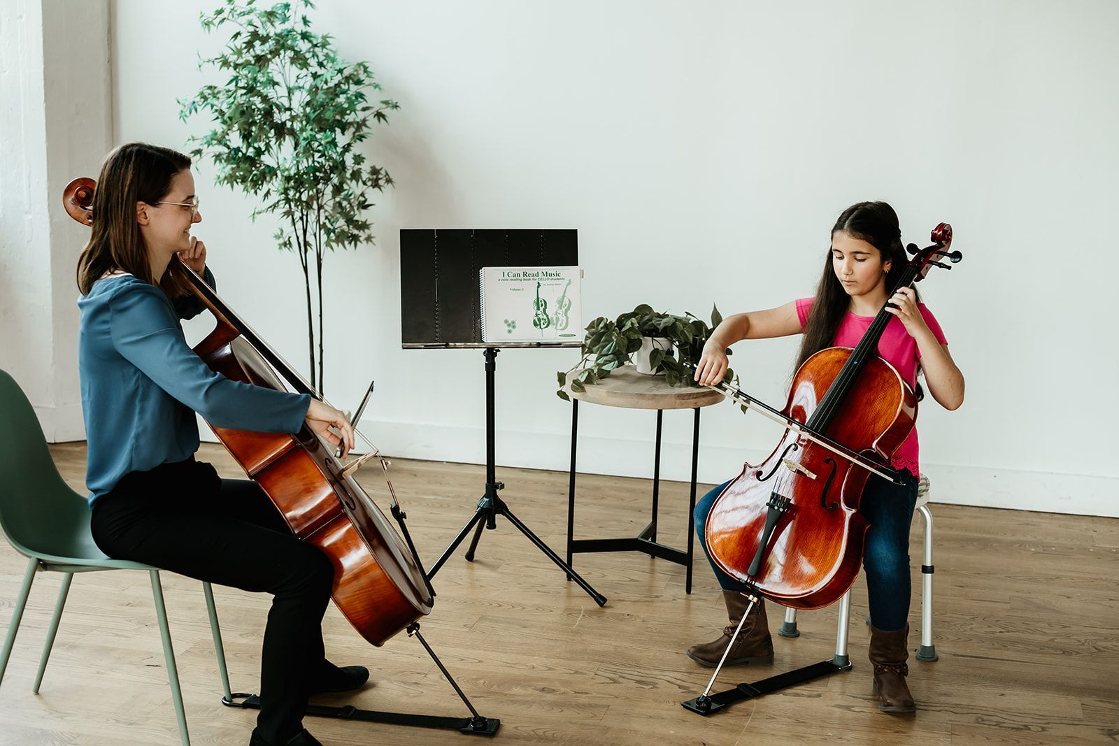 A young girl is playing cello with her teacher during a private lesson 