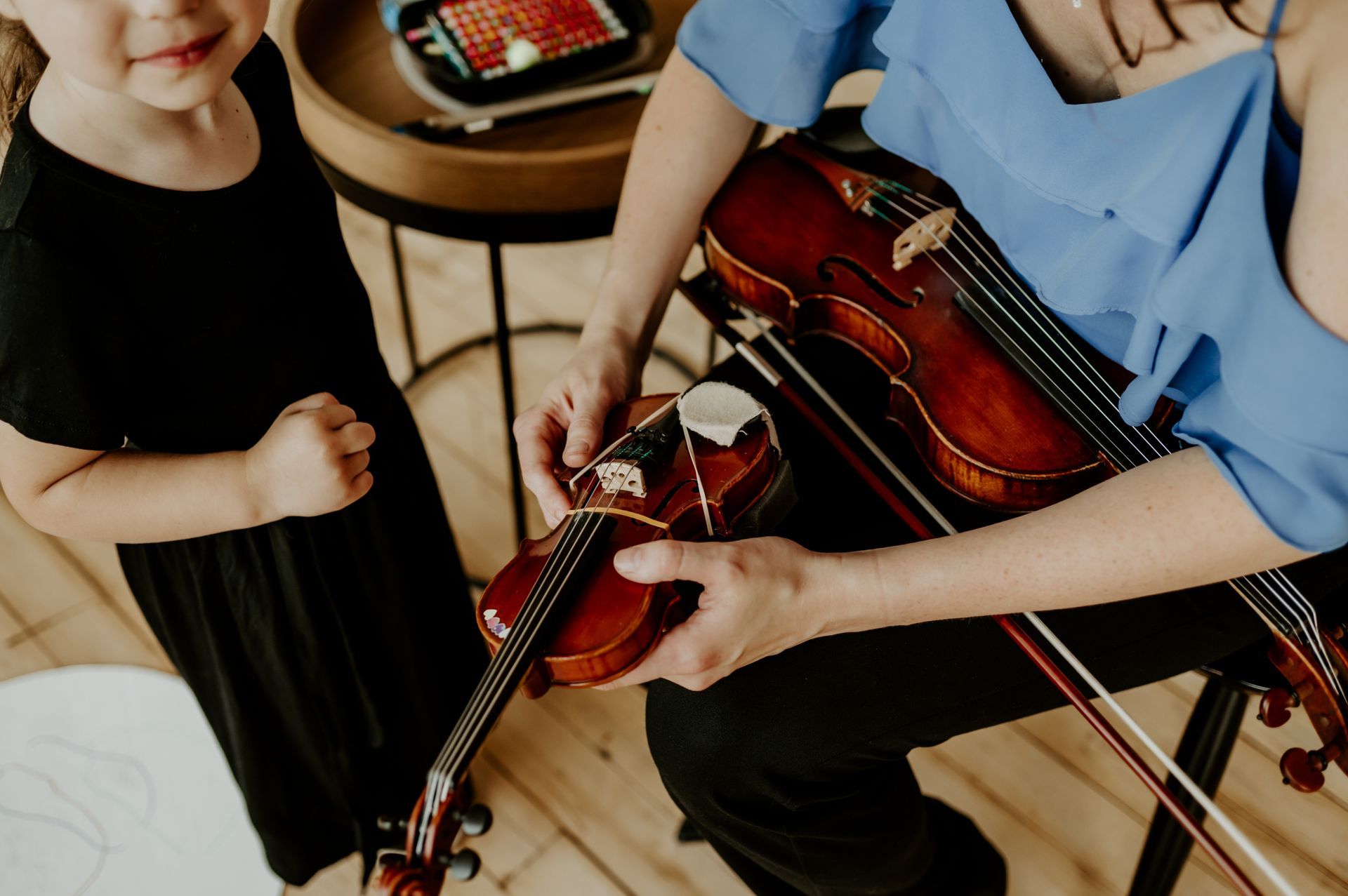 Violin teacher assisting a young student during a homeschool music lesson at Lakewood Suzuki Strings