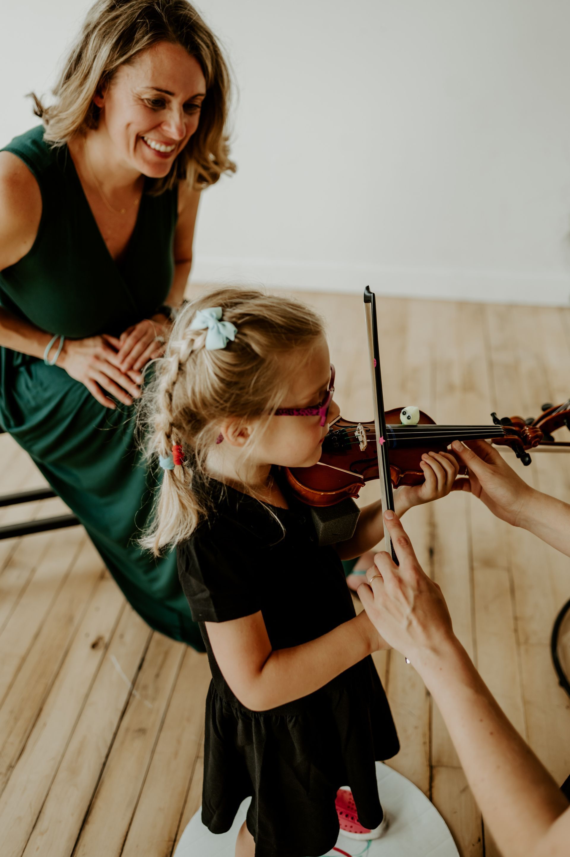 student practicing violin with her mom at home