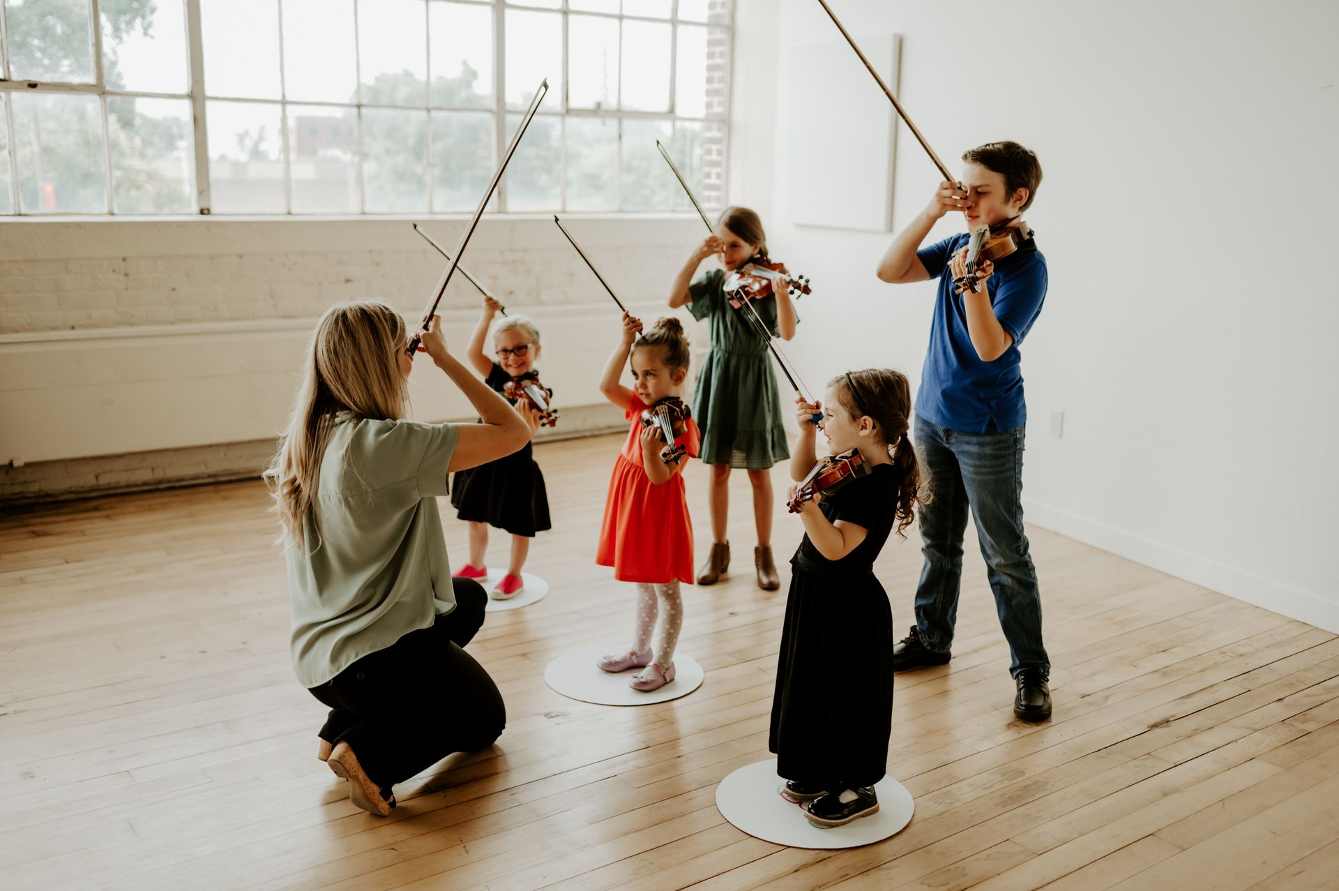 A class of children are standing in a group holding violins.
