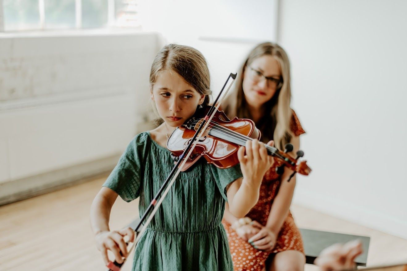 violin student in a private lesson practicing with her mom at home