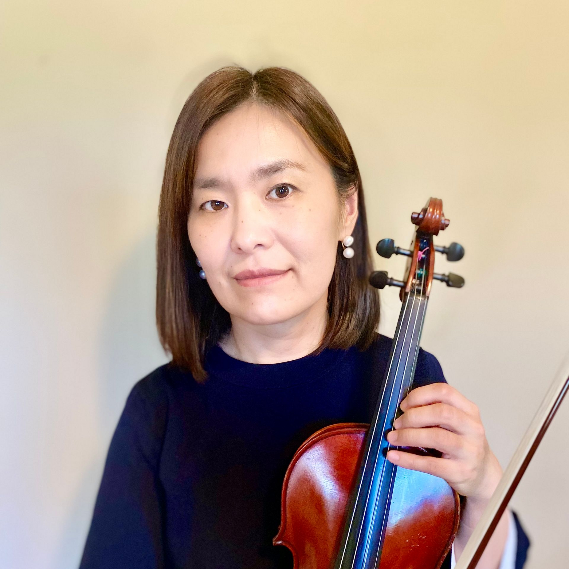 A woman in a green dress is holding a violin and smiling.