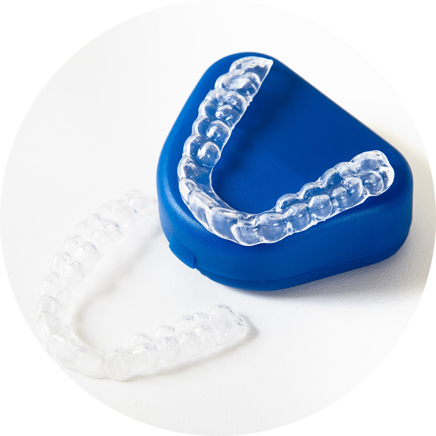 Clear orthodontic retainers, one in a blue case and one beside.