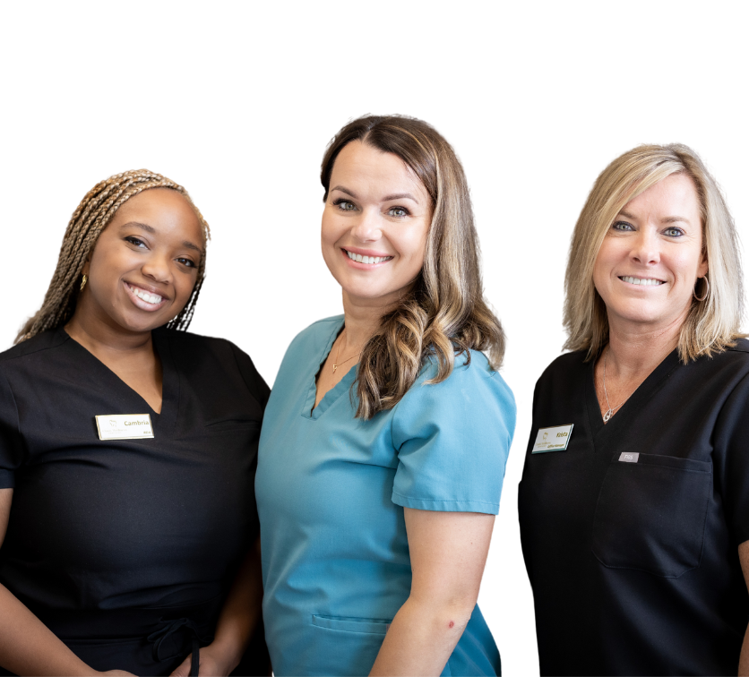 Three healthcare workers smiling in scrubs.