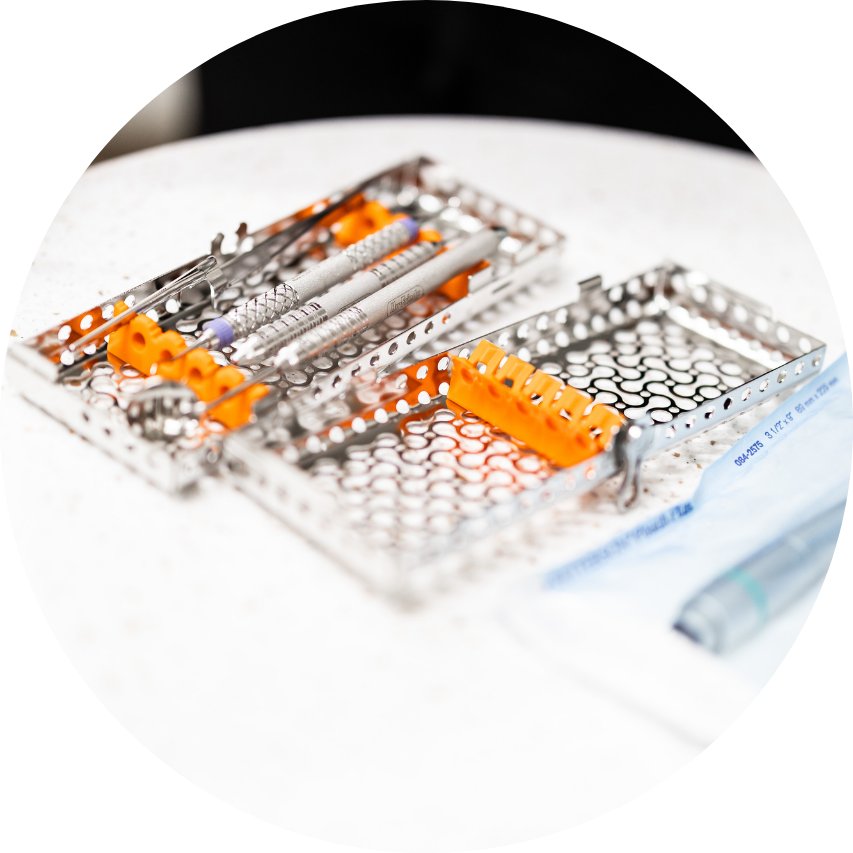 Dental instruments in metal trays on a white surface.