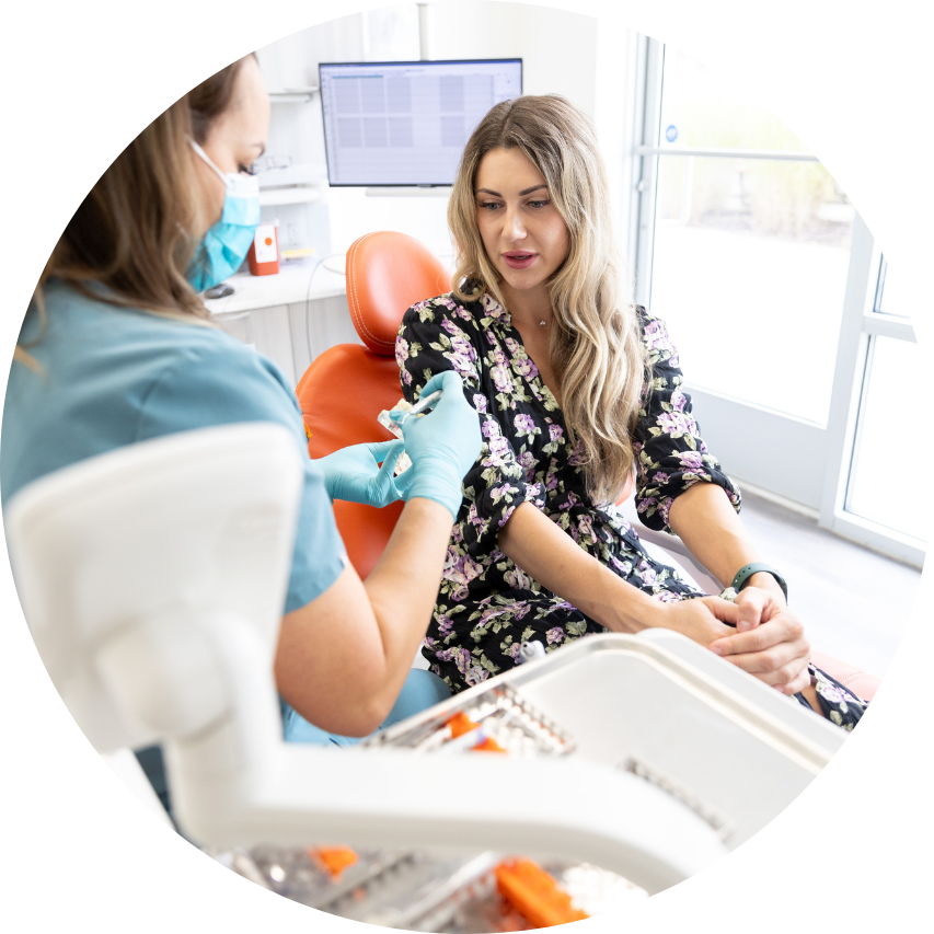 Dentist preparing an injection for a patient seated in a dental chair in a bright office.