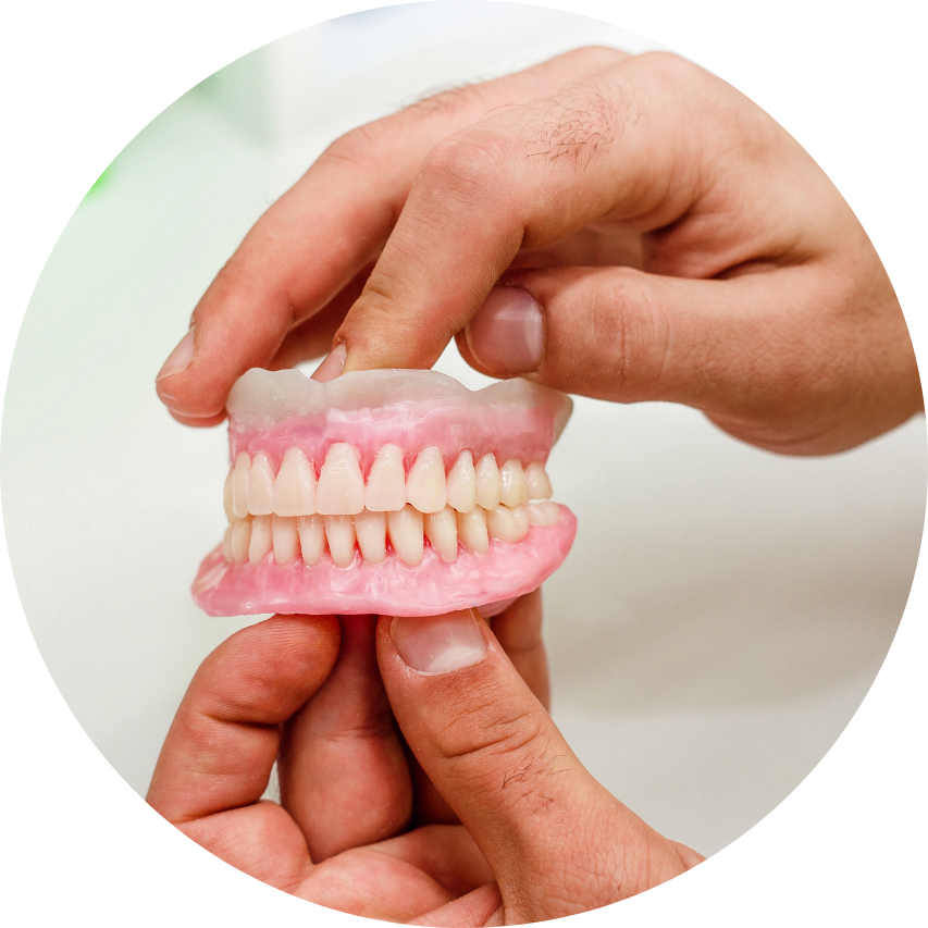 Hands holding a set of dentures, showing the pink gum and white teeth.