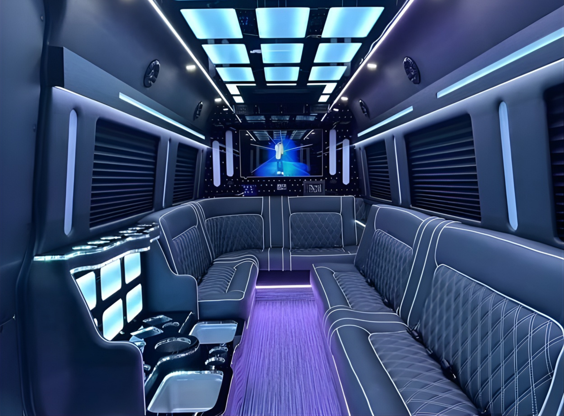 Interior of a luxury van with blue LED lights, diamond-stitched seating, and a large screen.
