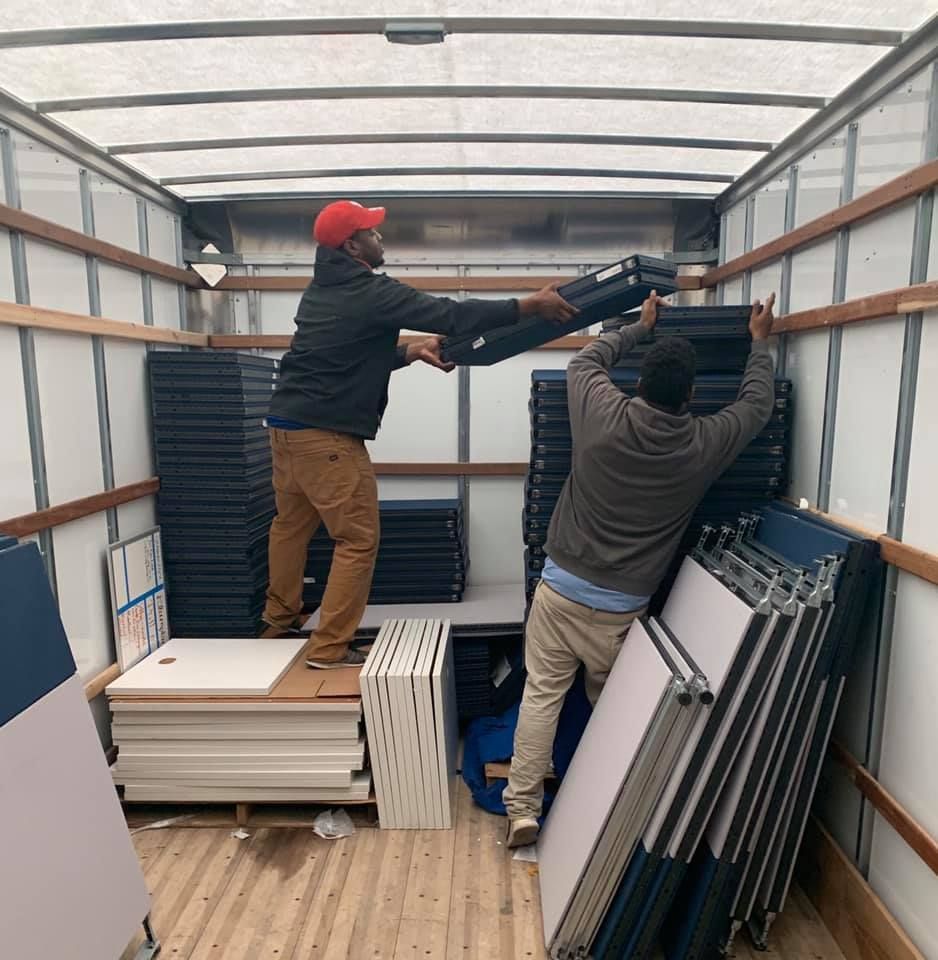 Two men are loading a stack of boxes into a truck. 28.4845° N, 81.2519° W