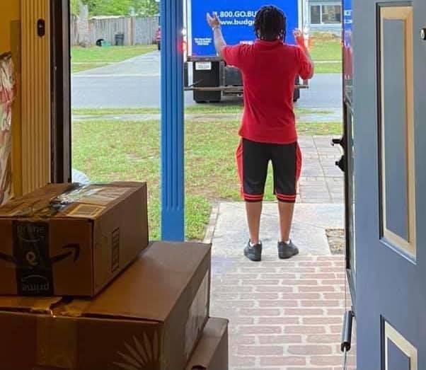A man in a red shirt is standing in front of a blue truck. 28.4845° N, 81.2519° W