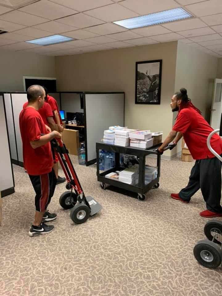 A group of men are moving a cart in an office.