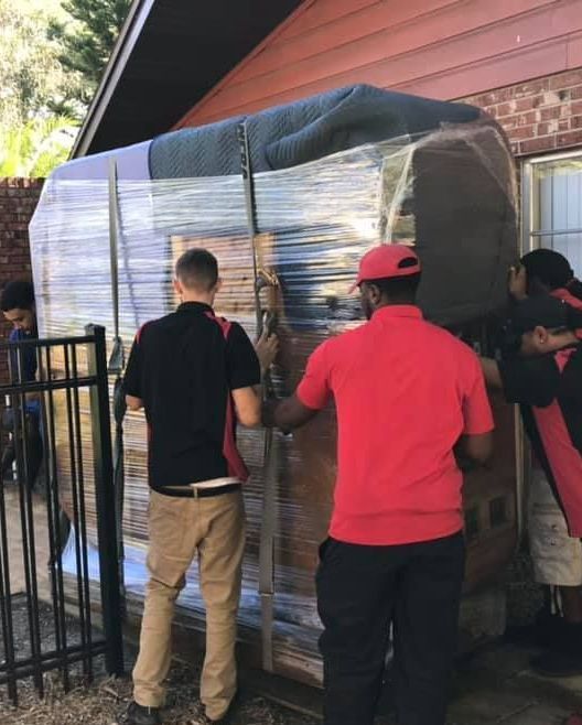 A man in a red shirt is carrying a large box 28.4845° N, 81.2519° W