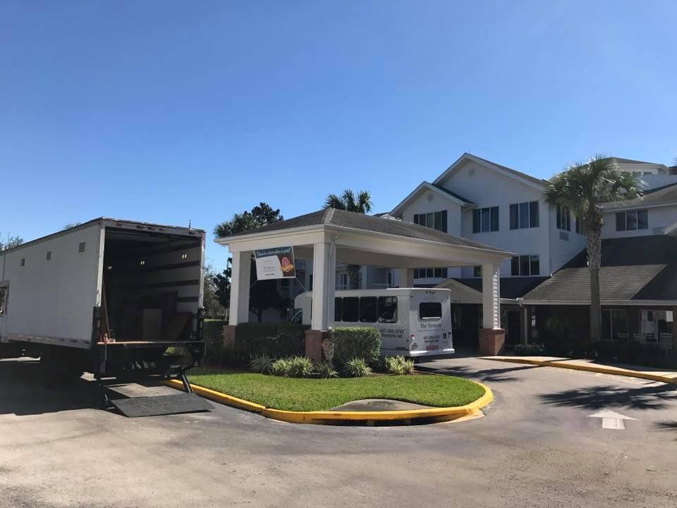 A white truck is parked in front of a large white building.