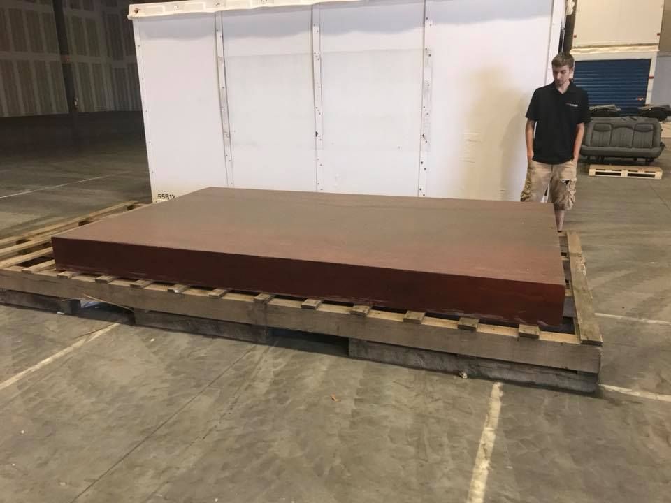 A man is standing next to a large piece of wood in a warehouse. 28.4845° N, 81.2519° W