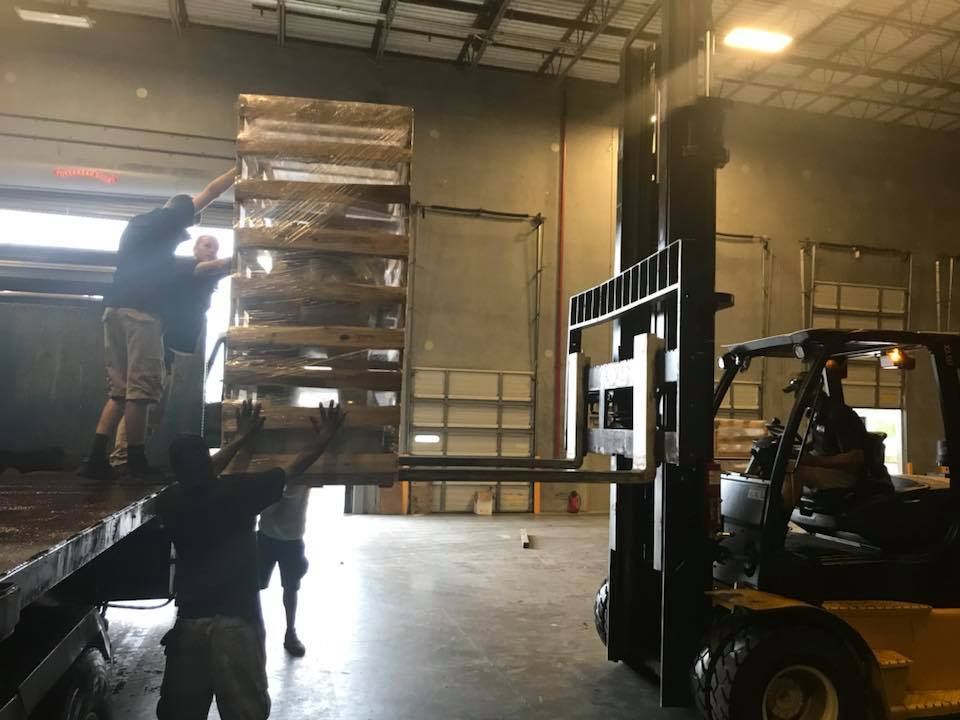 A forklift is lifting a stack of wooden pallets in a warehouse. 28.4845° N, 81.2519° W