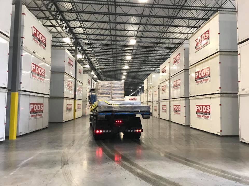 A truck is driving through a warehouse filled with containers. 28.4845° N, 81.2519° W