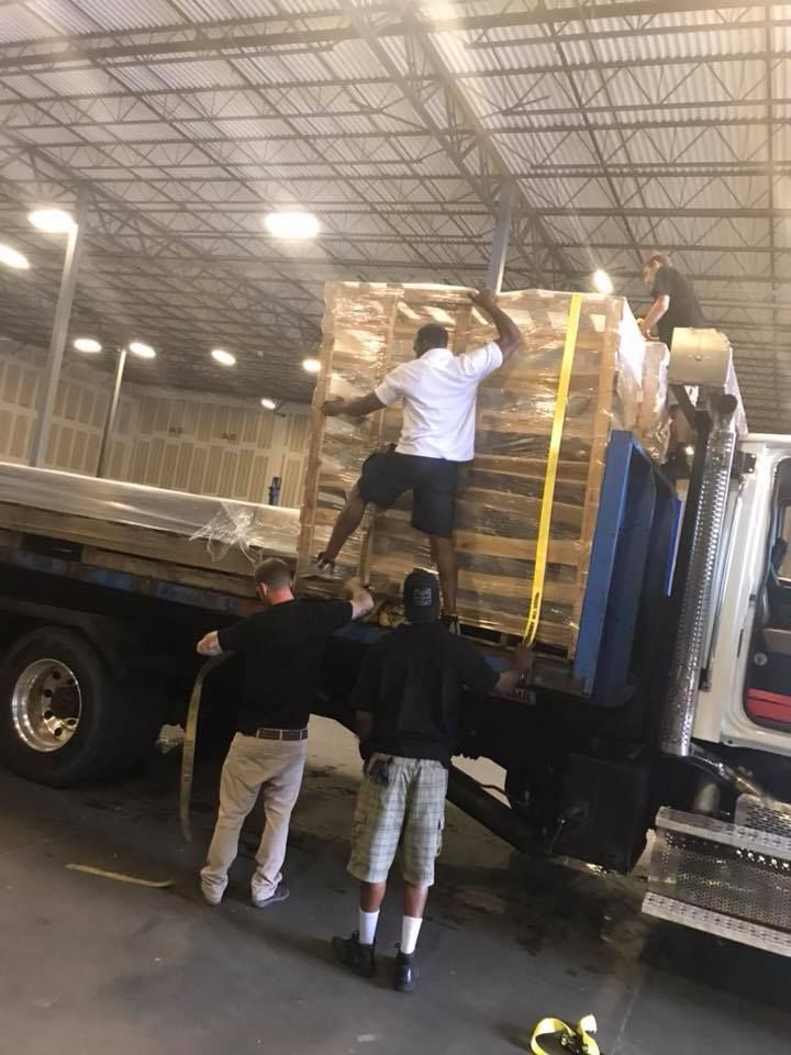 A group of men are loading a large pallet onto a truck. 28.4845° N, 81.2519° W