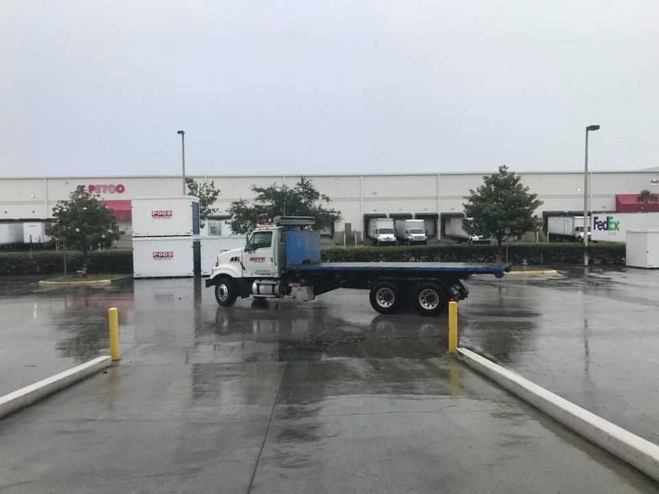 A flatbed truck is parked in a wet parking lot 28.4845° N, 81.2519° W