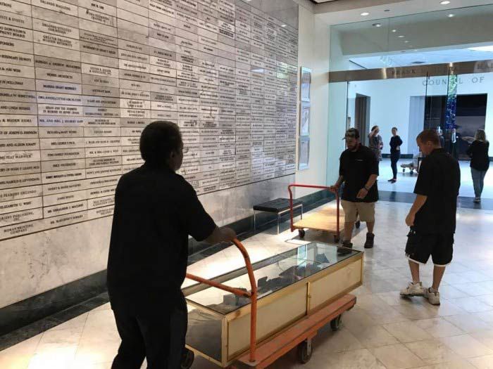 A group of men are moving a display case on a cart.28.4845° N, 81.2519° W