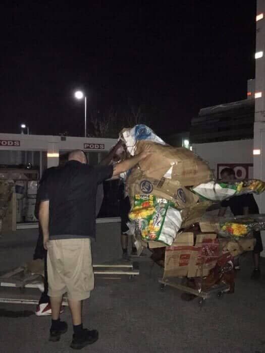 A man is standing next to a cart full of boxes and bags. 28.4845° N, 81.2519° W