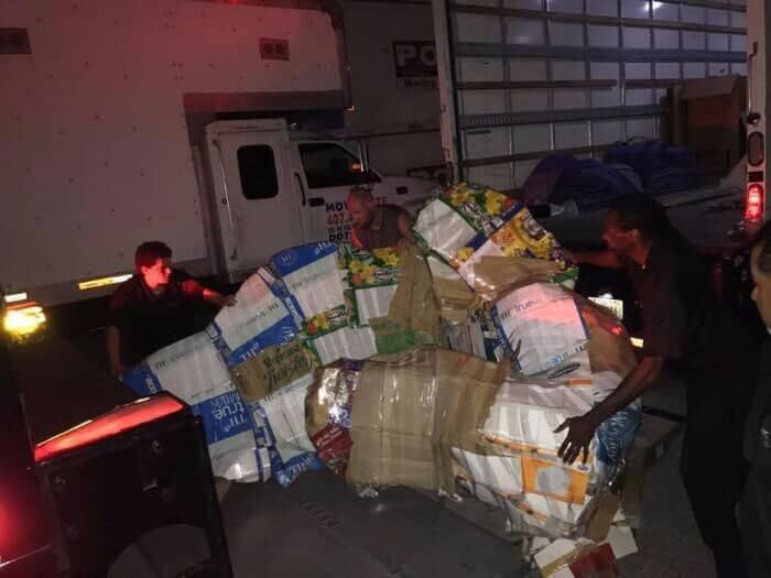 A man is carrying a large pile of boxes in front of a truck. 28.4845° N, 81.2519° W