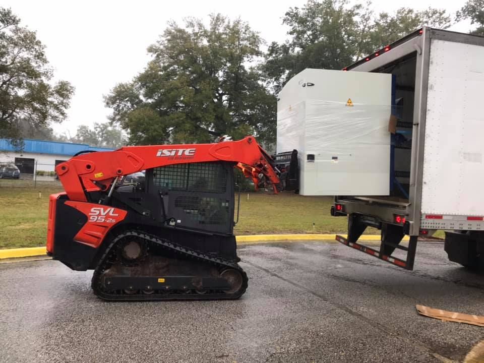 A small bulldozer is being towed by a truck 28.4845° N, 81.2519° W