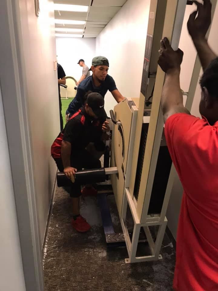 A group of men are moving a large piece of equipment in a hallway. 28.4845° N, 81.2519° W