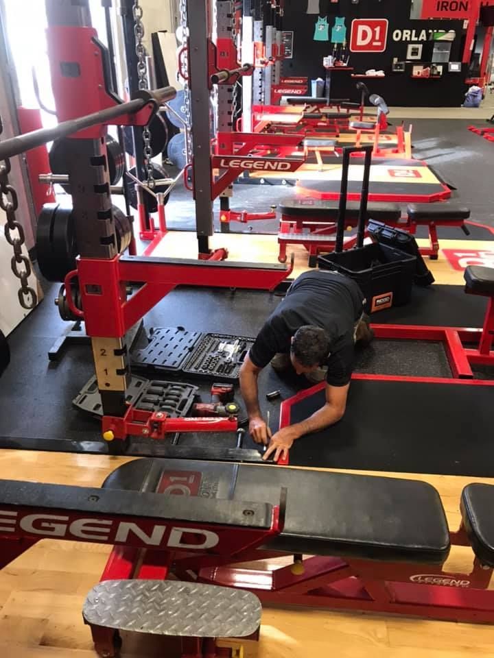 A man is working on a bench in a gym. 28.4845° N, 81.2519° W