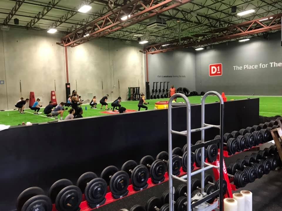 A group of people are doing squats in a gym. 28.4845° N, 81.2519° W