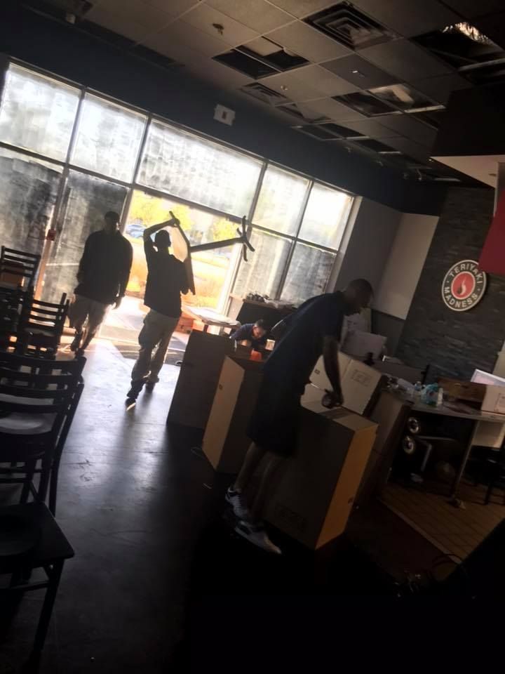 A group of people are standing in a restaurant with a pizza hut logo on the wall. 28.4845° N, 81.2519° W
