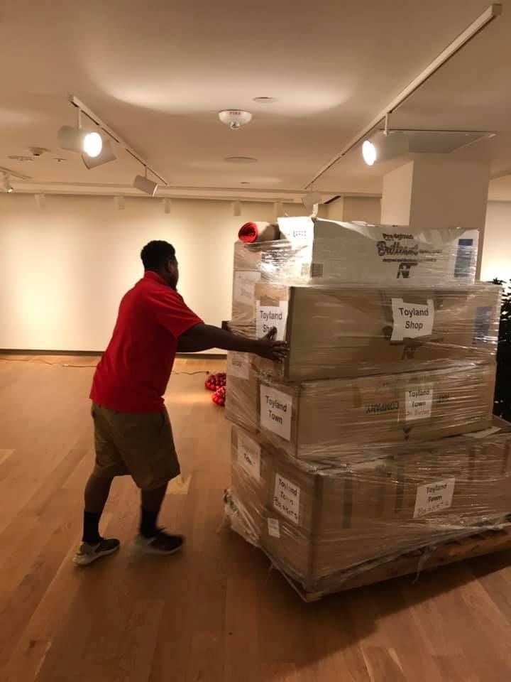 A man in a red shirt is pushing a cart full of boxes. 28.4845° N, 81.2519° W