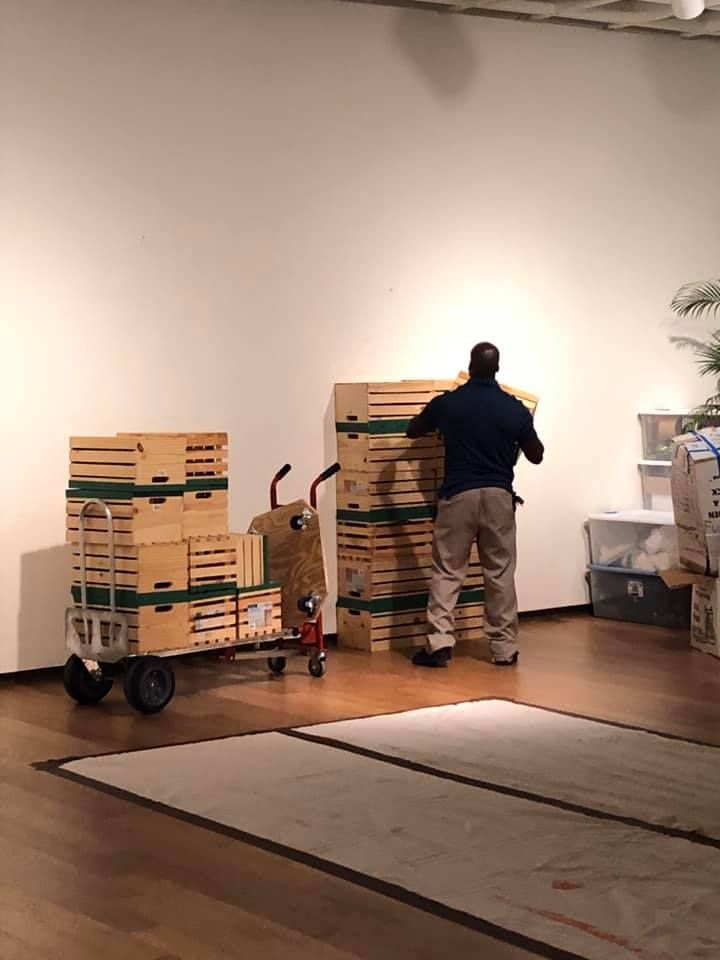 A man is loading boxes on a cart in a room 28.4845° N, 81.2519° W