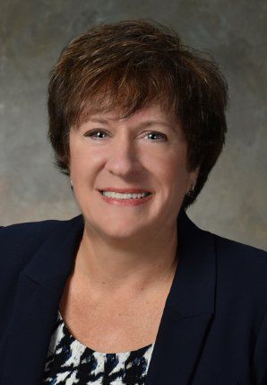 A woman is wearing a blue jacket and smiling for the camera.