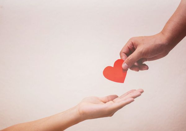 A person is giving a red heart to another person.