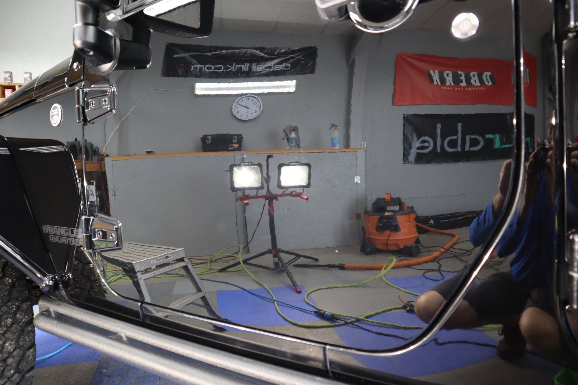 a person is kneeling down in front of a car in a garage .