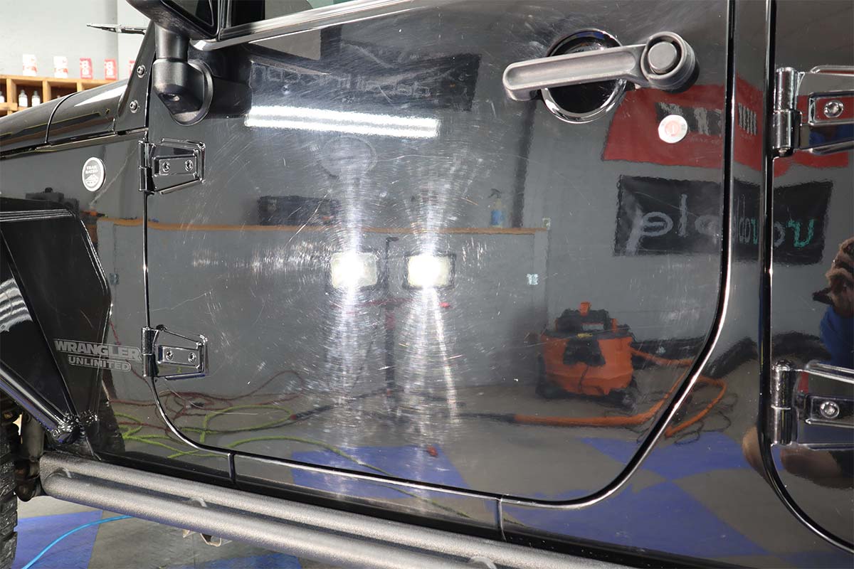 a close up of a black jeep door with a lot of scratches on it .