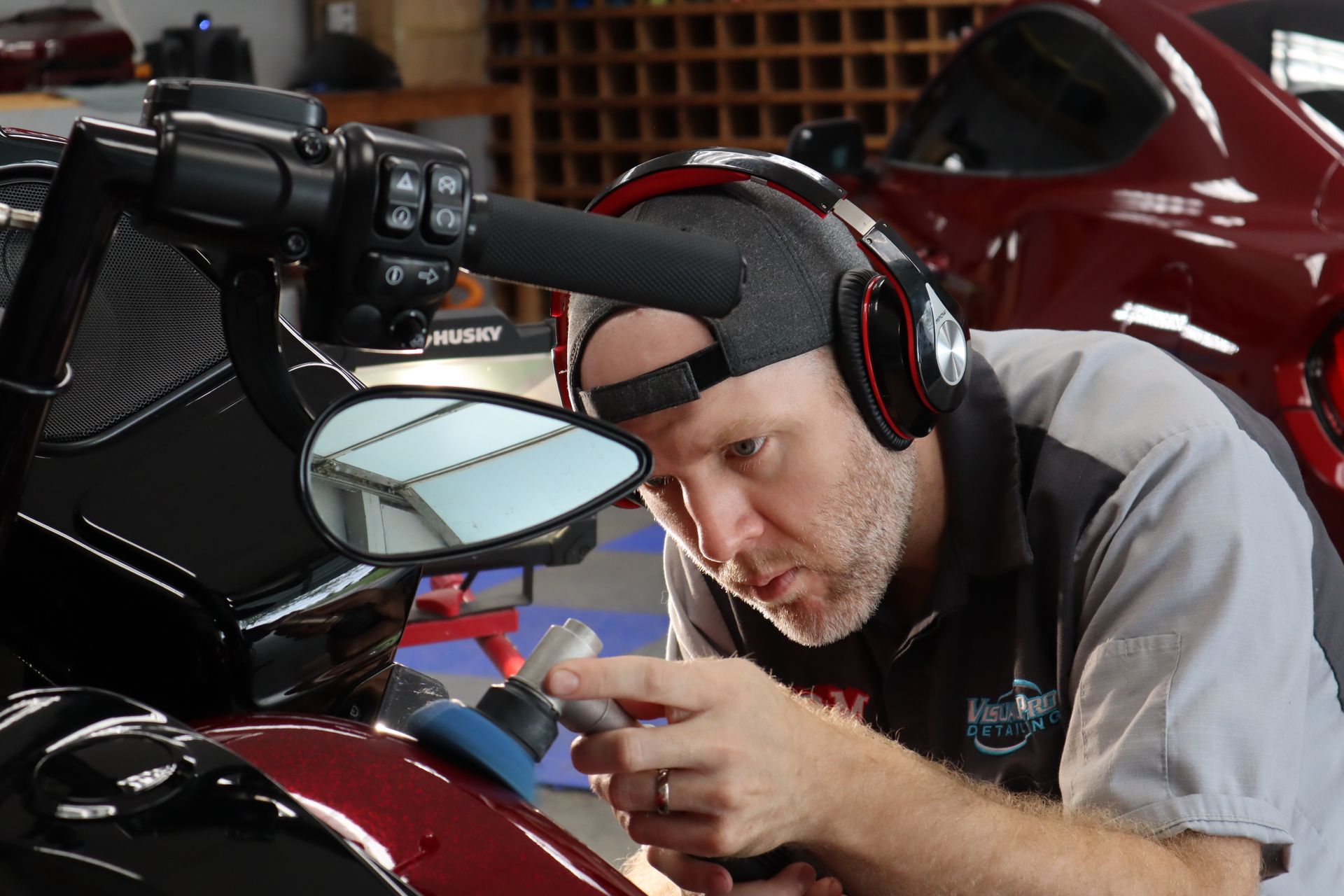 Mechanic wearing headphones inspecting a motorcycle with a handheld device in a garage