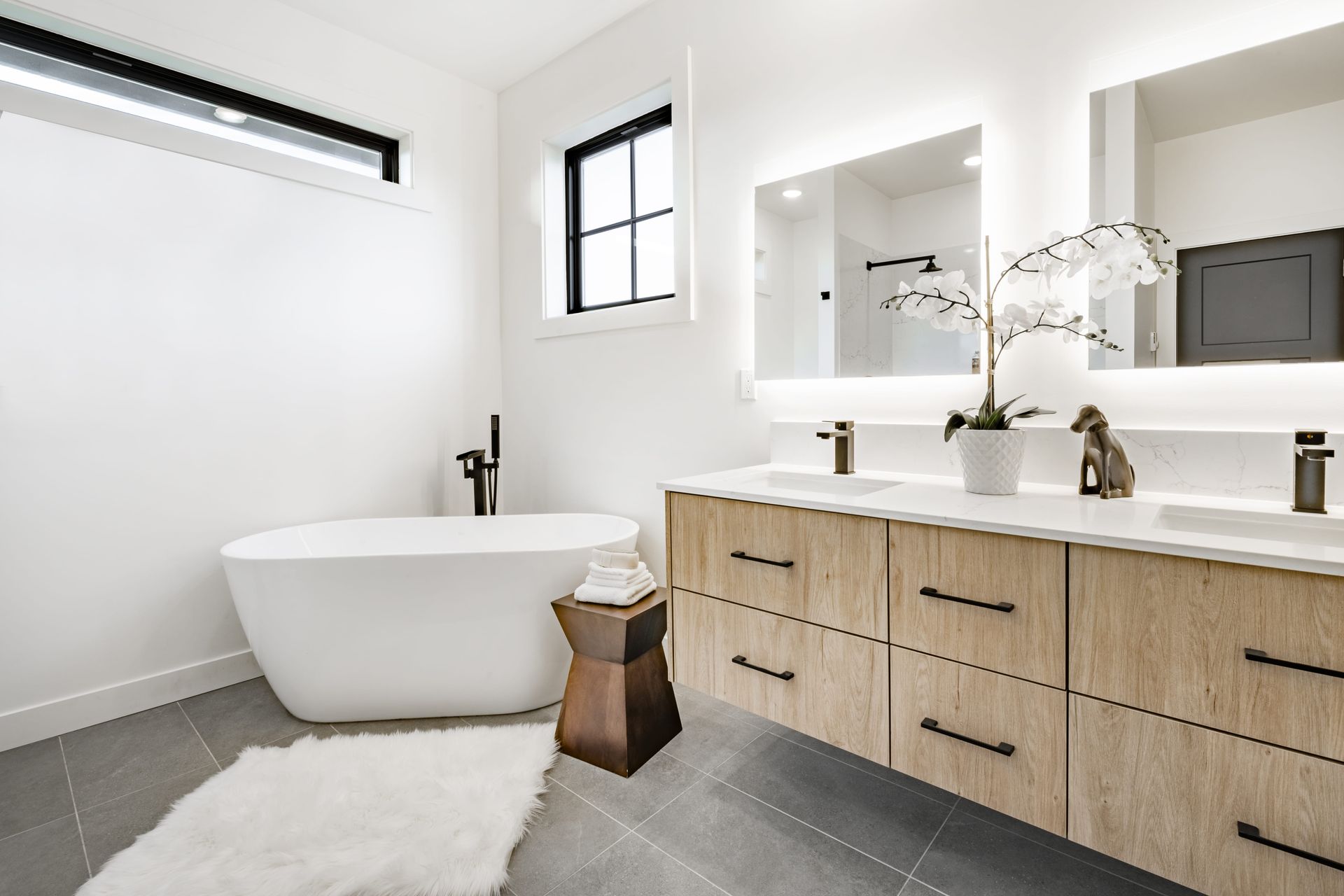 Modern bathroom with freestanding tub, double vanity, and white and wood finishes