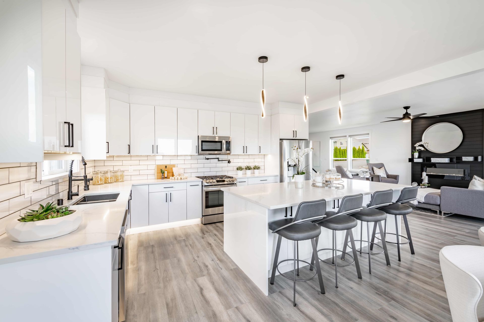 Bright modern white kitchen and dining area with island, bar stools, and gray accents