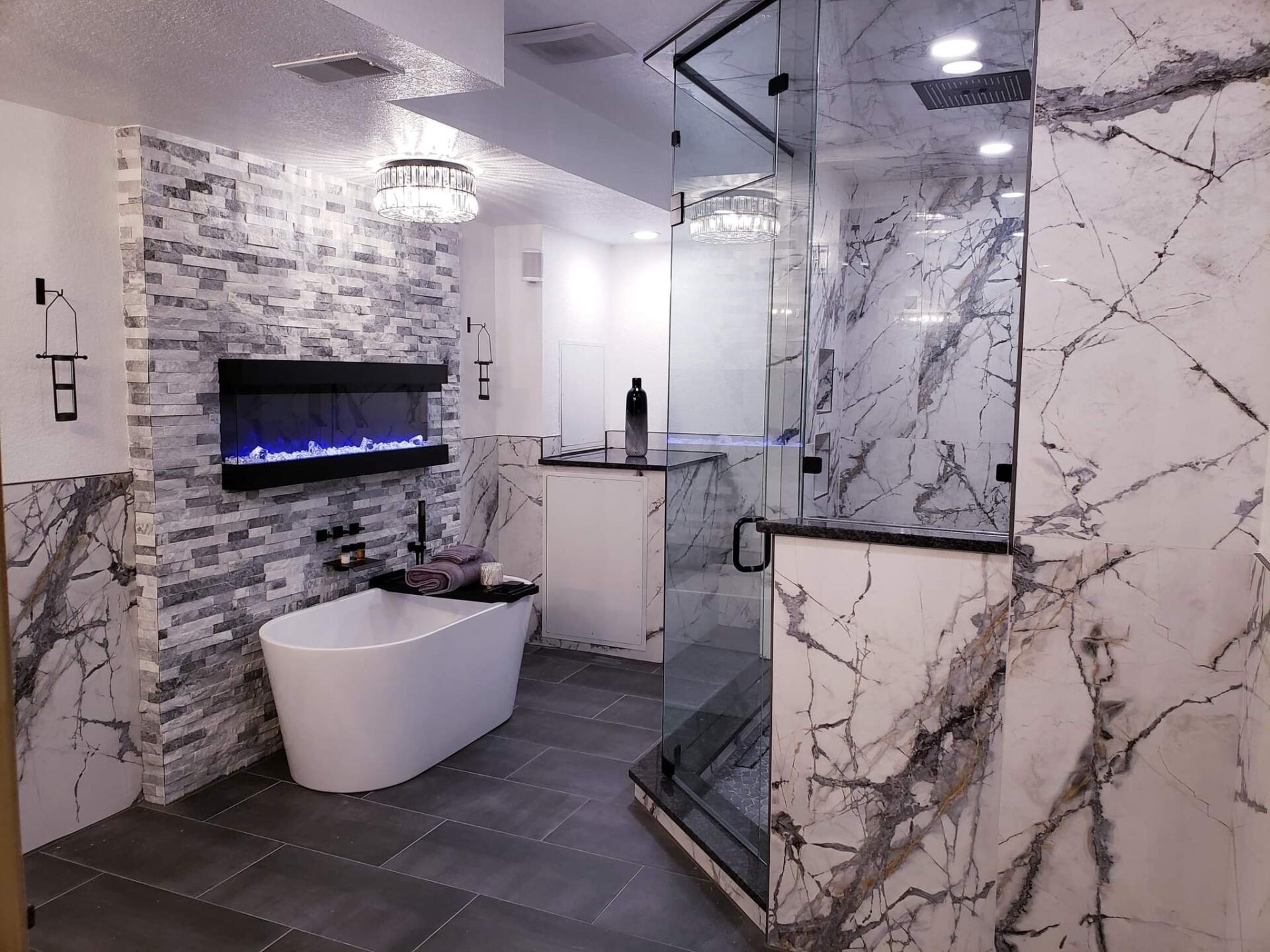 A bathroom with a tub , shower , fireplace and marble walls.